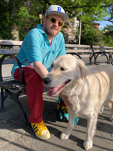 Justin Neely seated on a bench with a golden retriever